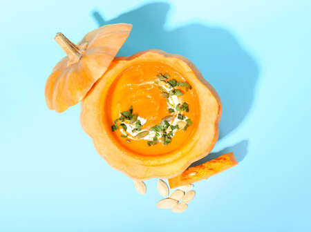 Tasty cream soup served in pumpkin and seeds on blue backgroundの写真素材