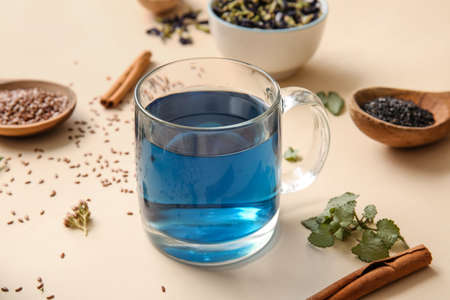 Glass cup of tasty blue tea and flax seeds on color background, closeupの写真素材