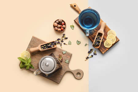 Composition with cup of blue tea, nuts and dried butterfly pea flowers on color backgroundの写真素材