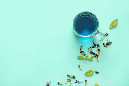 Cup of blue tea and dried butterfly pea flowers on color backgroundの写真素材