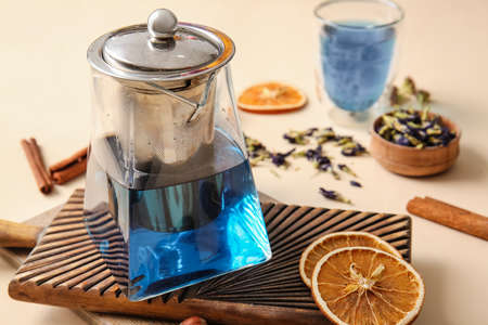 Teapot of tasty blue tea and dried fruits on color background, closeupの写真素材