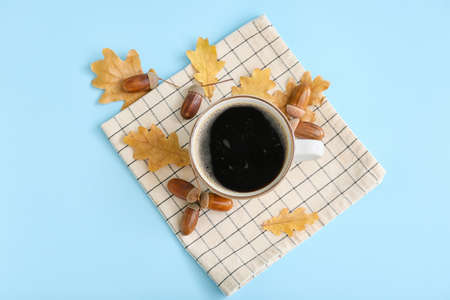 Cup of coffee with acorns and autumn leaves on blue backgroundの写真素材