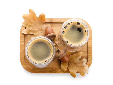 Glass cups of coffee with acorns and autumn leaves on white backgroundの写真素材