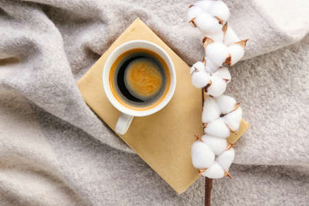 Cotton flowers, warm scarf, book and cup of coffee on light backgroundの写真素材