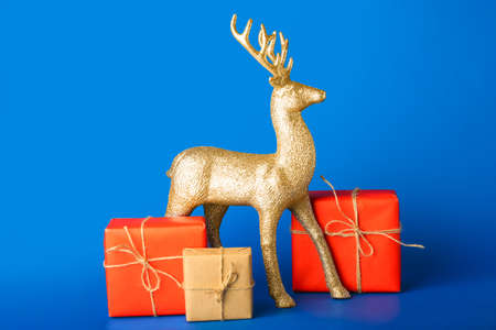 Golden reindeer with Christmas gifts on blue backgroundの写真素材