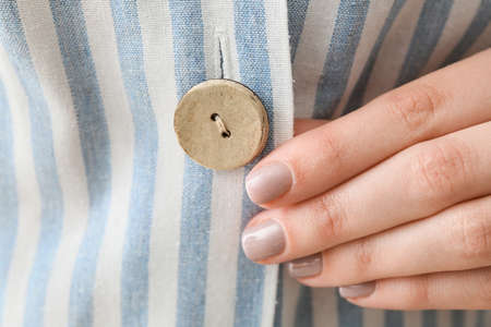 Woman buttoning up striped shirt, closeupの写真素材