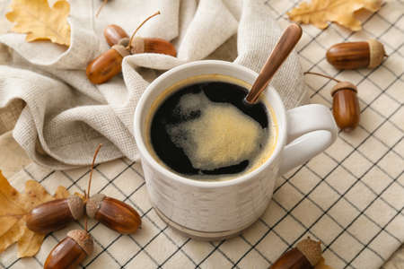 Cup of coffee with acorns and autumn leaves on tableの写真素材