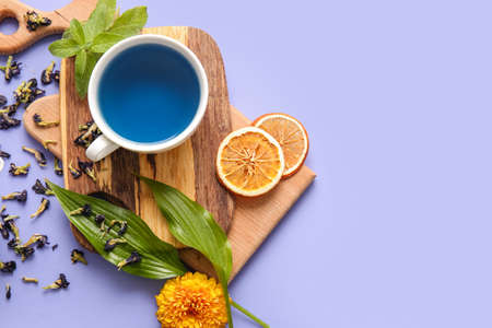 Cup of blue tea and dried butterfly pea flowers on color backgroundの写真素材