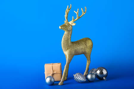 Golden reindeer with Christmas gift and balls on blue backgroundの写真素材