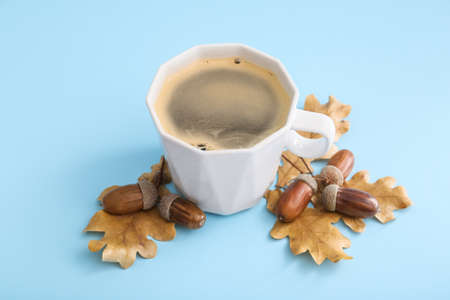 Cup of coffee with acorns and autumn leaves on blue backgroundの写真素材