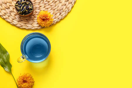 Cup of blue tea and dried butterfly pea flowers on yellow backgroundの写真素材