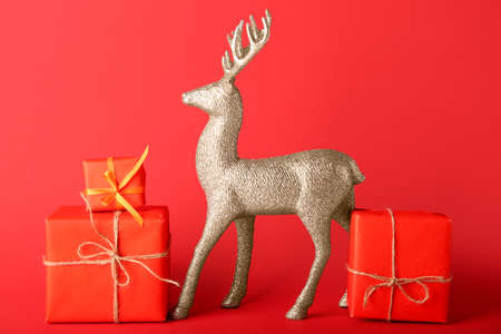 Golden reindeer with Christmas gifts on red backgroundの写真素材