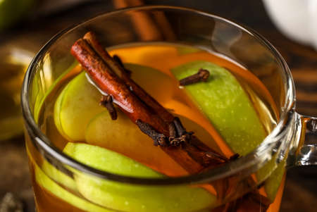 Glass cup of tasty fruit tea with cinnamon on wooden background, closeupの写真素材