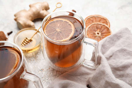Glass cups of tasty fruit tea with cinnamon on light background