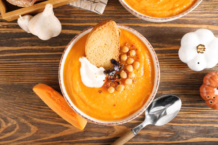 Bowl with delicious pumpkin cream soup on wooden backgroundの写真素材
