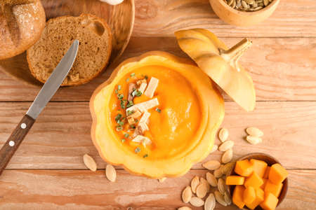 Delicious cream soup served in pumpkin and seeds on wooden backgroundの写真素材