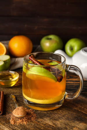 Glass cup of tasty fruit tea with cinnamon on wooden backgroundの写真素材