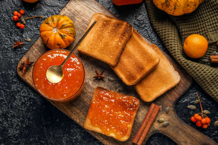 Bowl of sweet pumpkin jam with orange and toasts on black backgroundの写真素材