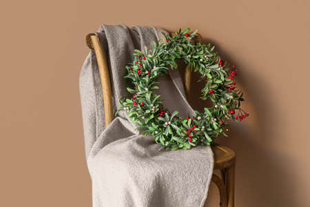 Chair with plaid and Christmas wreath hanging on color wall, closeupの写真素材