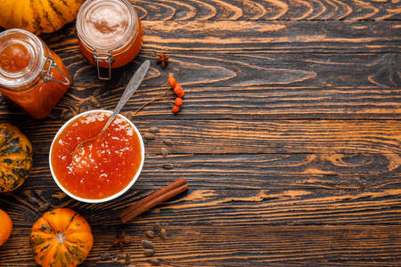 Bowl and jars of sweet pumpkin jam on wooden backgroundの写真素材
