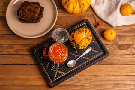 Jar of sweet pumpkin jam with oranges and toasts on wooden backgroundの写真素材