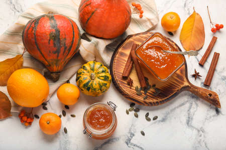 Bowl and jar of sweet pumpkin jam with oranges on white marble backgroundの写真素材
