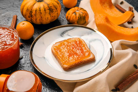 Plate of toast with sweet pumpkin jam and oranges on black backgroundの写真素材