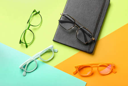 Set of eyeglasses and notebook on color backgroundの写真素材