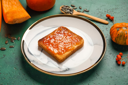 Plate of toast with sweet pumpkin jam on green backgroundの写真素材