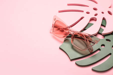 Stylish sunglasses and decorative palm leaves on color backgroundの写真素材