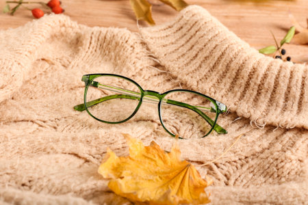 Eyeglasses and knitted sweater on wooden background, closeupの写真素材