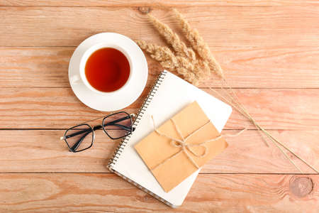 Composition with eyeglasses, cup of tea and card on wooden background