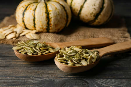 Spoons with pumpkin seeds on wooden backgroundの写真素材