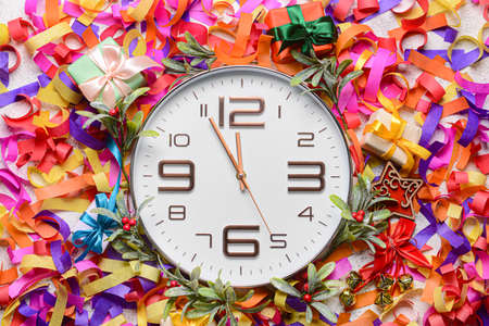 Stylish New Year clock with Christmas decor and serpentine on light background