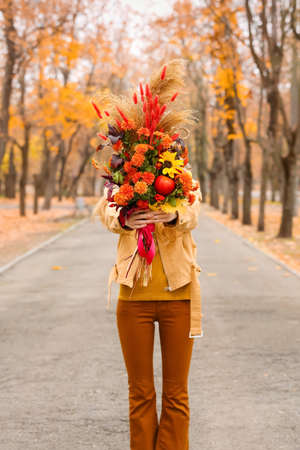 woman holding beautiful autumn bouquet in parkの写真素材