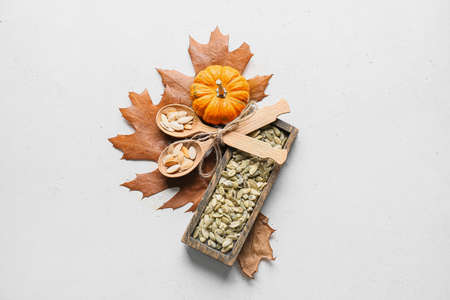 Wooden board and spoons with pumpkin seeds on white backgroundの写真素材