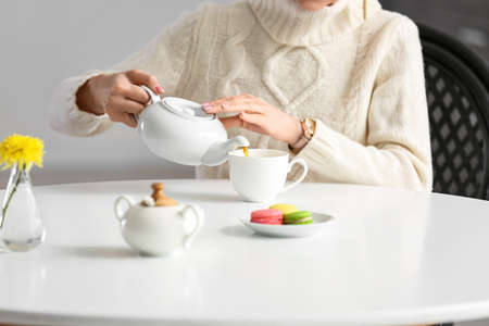 Young woman drinking tasty tea at table in cafeの写真素材