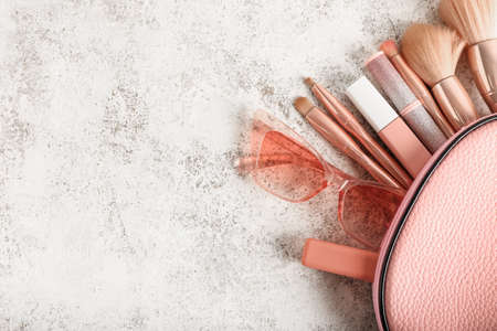 Cosmetic bag with stylish sunglasses, makeup brushes and cosmetics on light background, closeupの写真素材