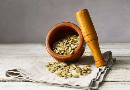 Mortar and pestle with pumpkin seeds on tableの写真素材