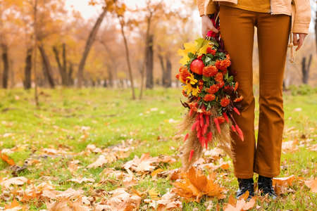 Woman with beautiful autumn bouquet standing on grass in parkの写真素材