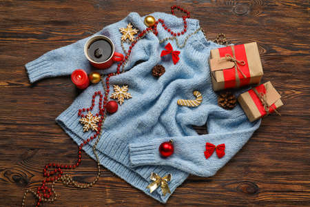 Stylish sweater, cup of coffee and Christmas decor on dark wooden backgroundの写真素材