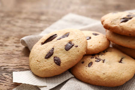 Delicious homemade cookies with chocolate chips on wooden background, closeup