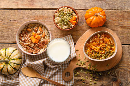 Bowls of tasty oatmeal with pumpkin on wooden backgroundの写真素材