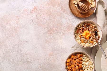 Bowls of tasty oatmeal with pumpkin and almond on light backgroundの写真素材