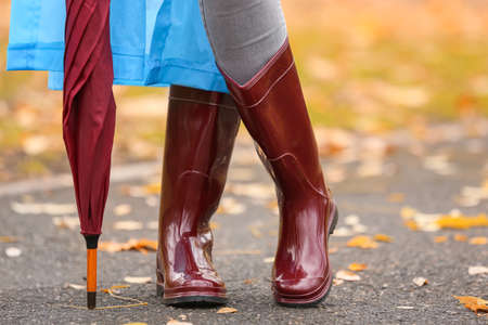 Young woman wearing gumboots in park on autumn dayの写真素材