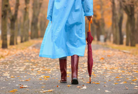 Young woman wearing gumboots in park on autumn dayの写真素材