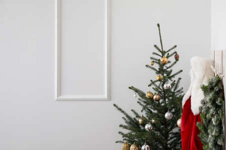 Christmas tree and hanger with Santa Claus costume in light hallwayの写真素材