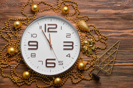 Stylish New Year clock with Christmas decor on wooden backgroundの写真素材