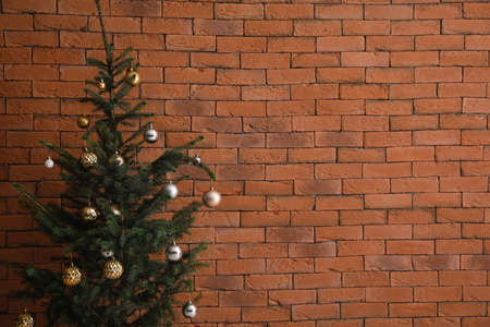 Beautiful decorated Christmas tree near brick wall in roomの写真素材