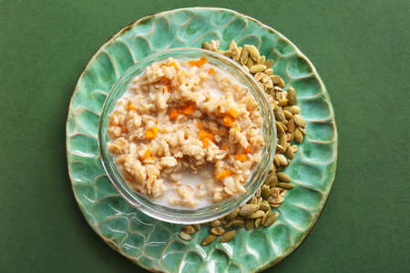 Bowl of tasty oatmeal with pumpkin on green backgroundの写真素材